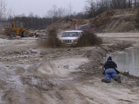 1995 Jeep Cherokee - A white SUV navigates a muddy track, kicking up a large spray of water and dirt.