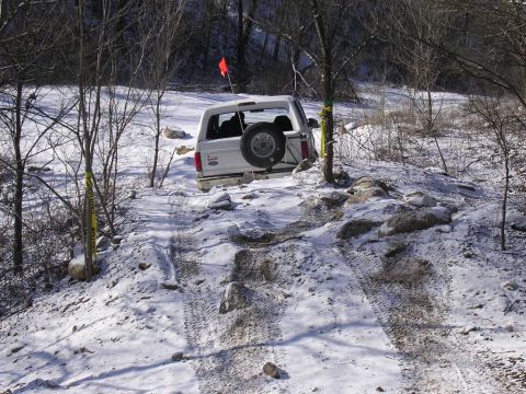 1995 Jeep Cherokee - This SUV is attempting to traverse a difficult, snow-covered path with large rocks.