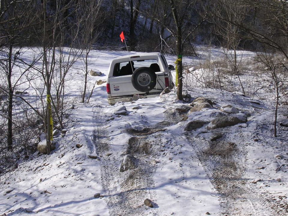 White SUV with spare tire on back navigating a snowy, rocky trail