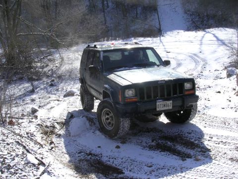 1995 Jeep Cherokee - A Jeep Cherokee navigates a snowy path with its tires kicking up snow.