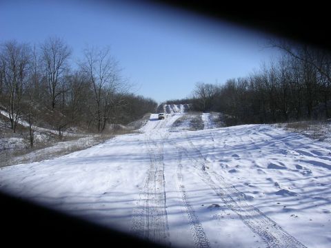 1995 Jeep Cherokee - Vehicles navigate a snowy path through a wooded area under a bright blue sky.