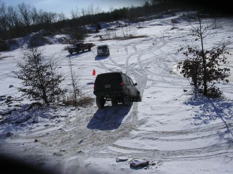 1995 Jeep Cherokee - Multiple off-road vehicles navigate a snow-covered hill, leaving tire tracks in their wake.