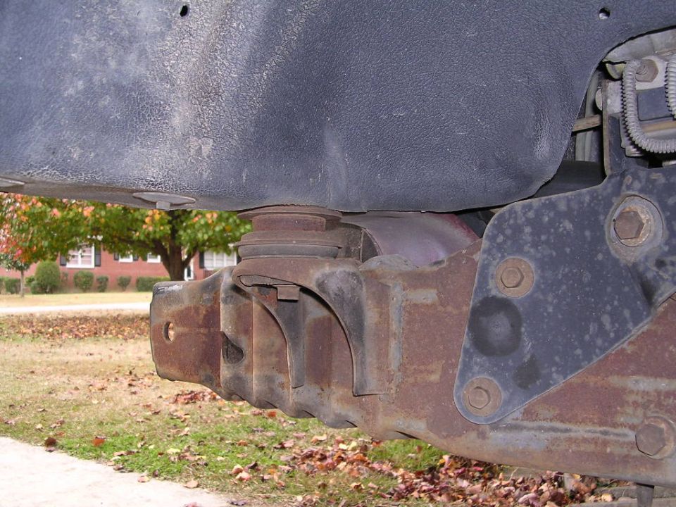 Close-up of rusty vehicle frame and suspension parts, possibly a body lift kit