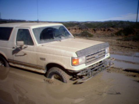 1990 Ford Bronco - This 1990 Ford Bronco is stuck in a muddy ditch, with only the front and part of the side visible.