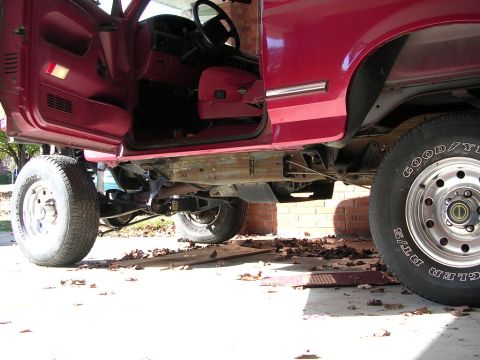 1995 Ford Bronco - The underside of a red SUV is visible, with its suspension system and large tires prominently displayed.