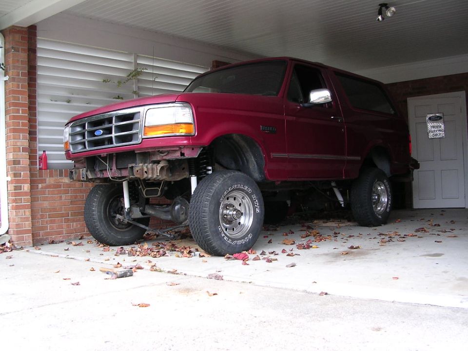 Maroon Ford Bronco in carport with front suspension extended and steering knuckle exposed