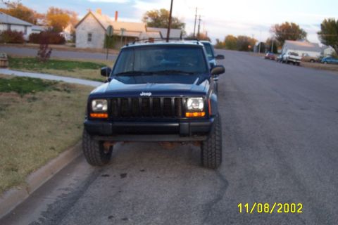 1998 Jeep Cherokee - A dark blue Jeep Cherokee is parked on the side of a street with houses in the background.