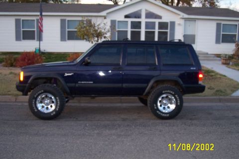 1998 Jeep Cherokee - This 1998 Jeep Cherokee is shown in profile, a dark blue exterior and modified suspension with larger wheels.