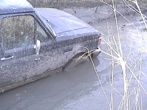 1989 Ford Bronco - Muddy 1989 Ford Bronco submerged in water, stuck off-road.
