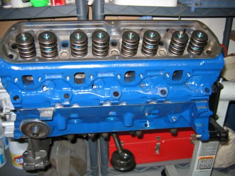 1992 Ford Bronco - A freshly rebuilt V8 engine block painted bright Ford blue, viewed from the side showing one cylinder head with valve springs and retainers…
