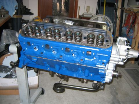 1992 Ford Bronco - A freshly rebuilt V8 engine block painted Ford blue, mounted on an engine stand with cylinder heads installed showing exposed valve springs…