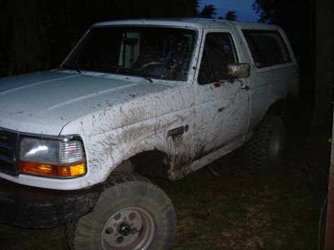 1993 Ford Bronco - This white Ford Bronco is heavily covered in mud, obscuring some of its details.