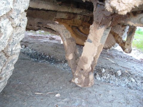 1989 Ford Bronco - Underside view of a heavily mud-caked vehicle frame and tire.
