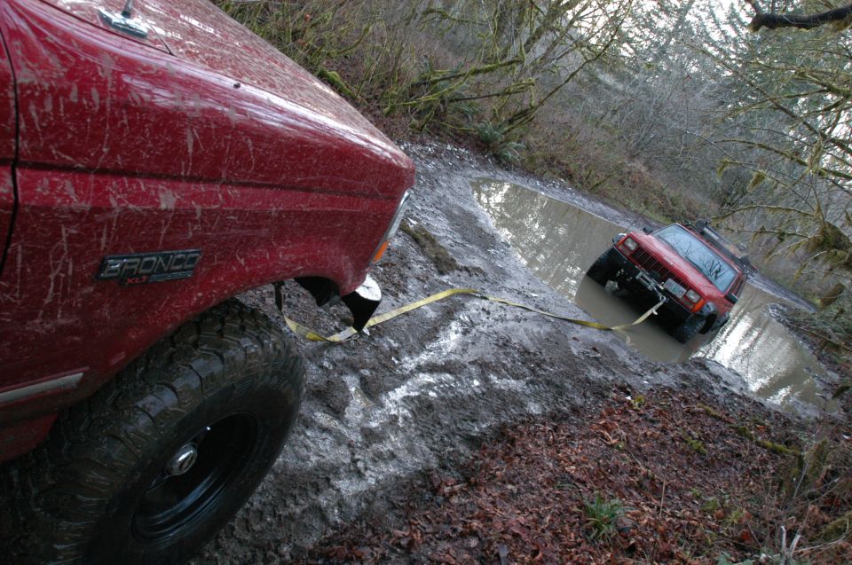 Red 1995 Ford Bronco stuck in mud, another SUV in ditch
