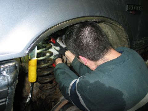 1995 Ford Bronco - A person works on the suspension of a vehicle, likely a Ford Bronco, with a visible XLT badge.