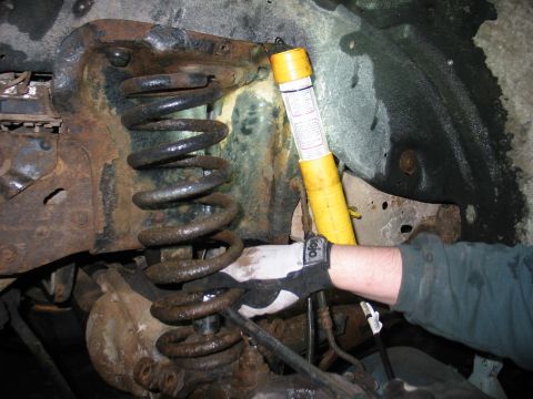 1995 Ford Bronco - Inspecting the heavily rusted suspension components of a vehicle, including a coil spring and shock absorber.
