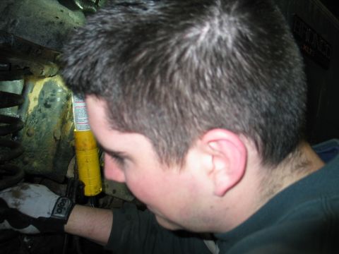 1995 Ford Bronco - A person examines the suspension components of a vehicle, illuminated by a yellow flashlight.
