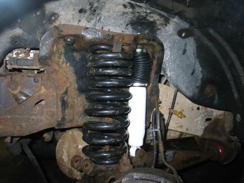 1995 Ford Bronco - Close-up of heavily rusted suspension components, including a coil spring and shock absorber.