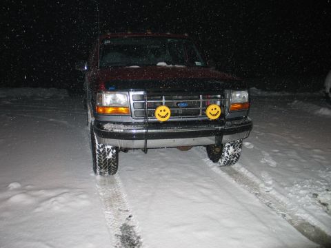 1995 Ford Bronco - A 1995 Ford Bronco is parked in the snow at night, equipped with yellow smiley face fog lights.