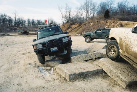 1995 Ford Bronco - Several off-road vehicles tackle a challenging obstacle course made of concrete blocks.