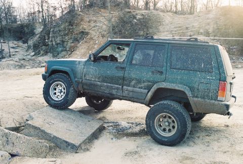 1995 Ford Bronco - This Jeep Cherokee XJ is navigating an off-road course with a rocky incline in the background.