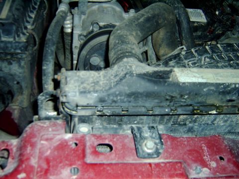 1998 Jeep TJ - Close-up of engine bay components including radiator and hoses, with a Supermotors logo.