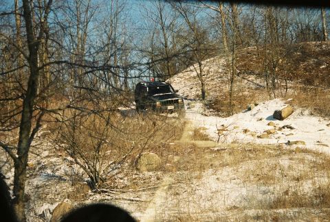 1995 Ford Bronco - A black SUV navigates a snowy, wooded path during winter.