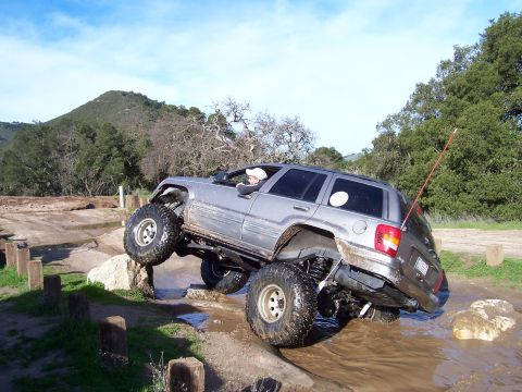 1998 Ford Ranger - A modified Jeep Grand Cherokee tackles a challenging water and rock obstacle during an off-road excursion.