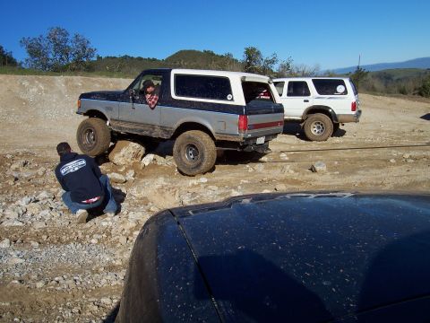 1998 Ford Ranger - A two-tone Ford Bronco navigates a rocky obstacle course with another SUV in the background.