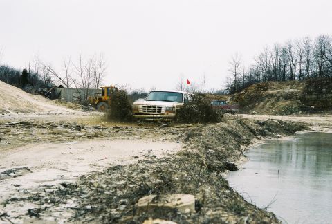 1995 Ford Bronco - Ford Bronco navigating a muddy obstacle course with a loader nearby.