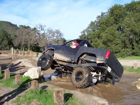 1998 Ford Ranger - A modified truck navigates a challenging off-road course with one wheel lifted high.