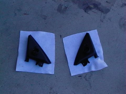 1999 Ford Taurus - Two black plastic automotive trim pieces are shown on a gray surface, each on a white paper square.