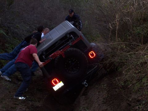 1998 Ford Ranger - People attempt to right an overturned off-road vehicle stuck in muddy terrain.