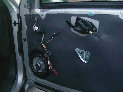 1999 Ford Taurus - The interior of a car door panel is shown with the speaker removed and wiring exposed.