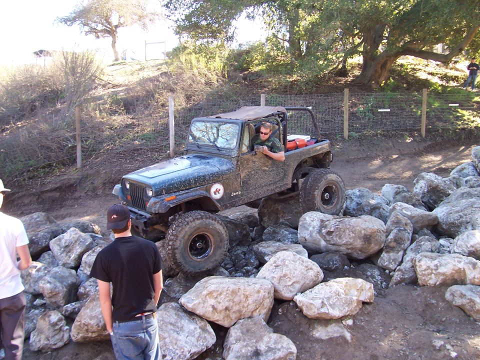 Dark green Jeep Wrangler TJ navigating rocks