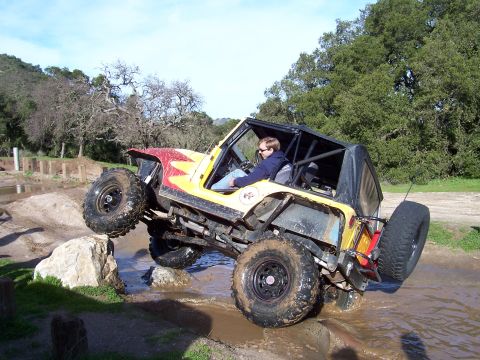 1998 Ford Ranger - Off-road vehicle with a driver navigates a challenging muddy terrain with large rocks.