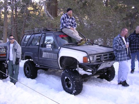 1999 Toyota Tacoma - A heavily modified Toyota 4Runner sits in the snow with several people around it.
