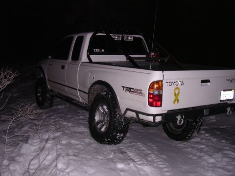1999 Toyota Tacoma - A white Toyota Tacoma is parked in a snowy area at night, showing its rear and side profile.