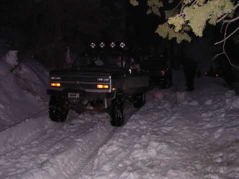 1999 Toyota Tacoma - Trucks navigate a snowy path at night, with one vehicle in the foreground and another behind it.