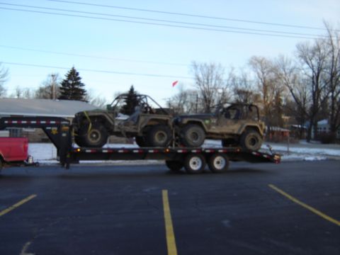 1992 Ford Bronco - A flatbed trailer carries two off-road vehicles, a buggy and a Jeep, ready for transport.