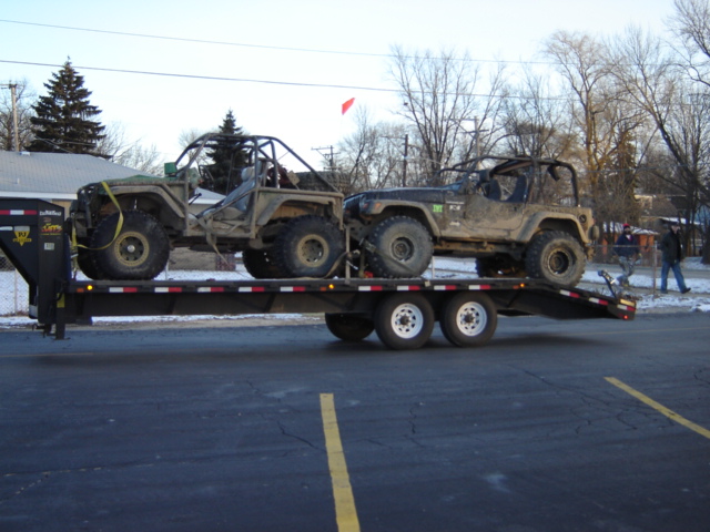 Two modified off-road Jeeps loaded onto a flatbed trailer