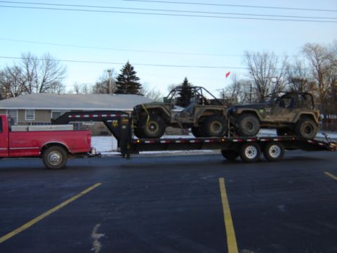 1992 Ford Bronco - A red pickup truck tows a gooseneck trailer carrying two off-road vehicles.