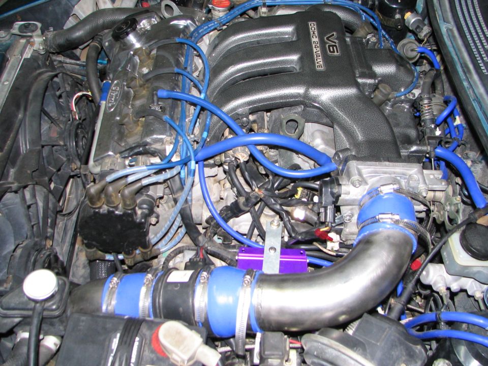 Engine bay with V6 DOHC 24-valve intake manifold, blue hoses, and Ford-branded valve cover