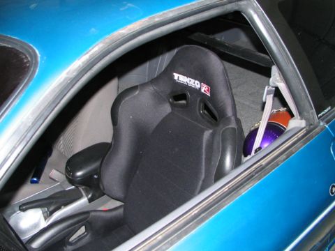 1994 Ford Probe - Close-up of a racing seat and helmet inside a blue vehicle's interior.