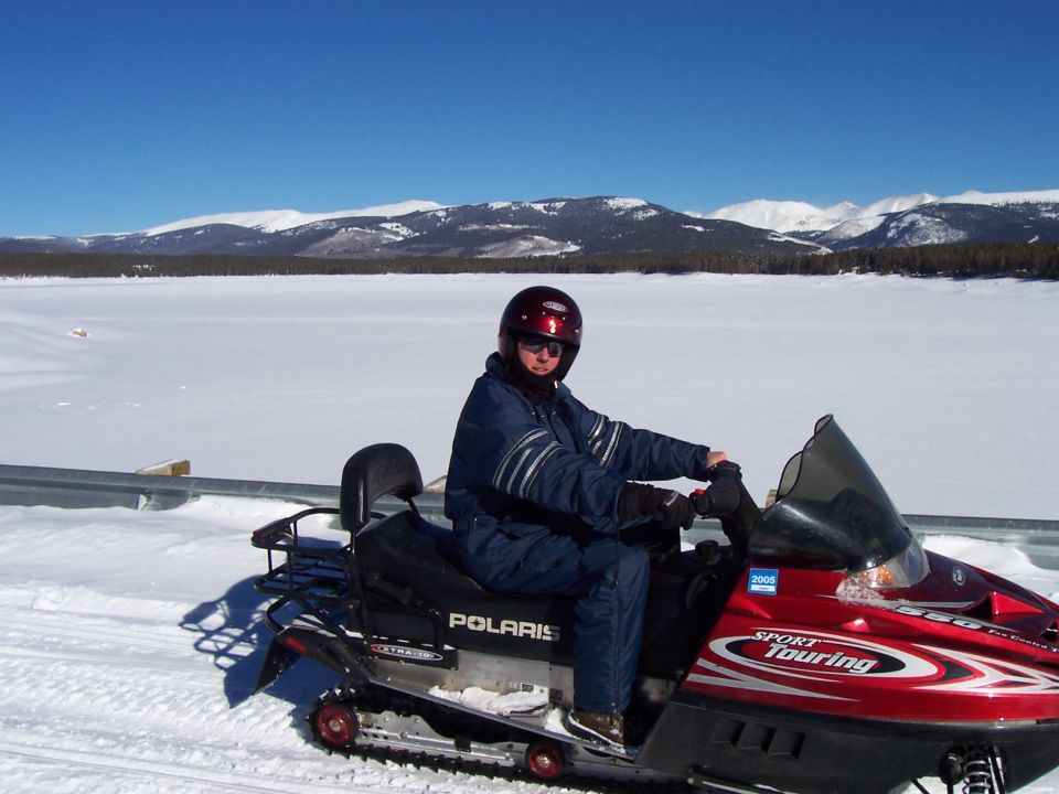 Red Polaris Sport Touring snowmobile with a person wearing a blue snowsuit and red helmet