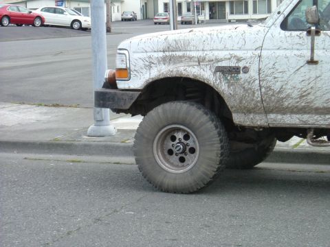 1993 Ford Bronco - A muddy 1993 Ford Bronco is shown from the front quarter, with the 'Bronco' badge visible on the fender.