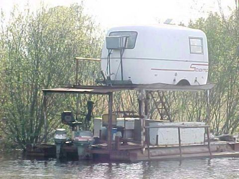 1979 Ford Bronco - A unique homemade houseboat constructed from a pontoon base, topped with a camper shell and equipped with multiple outboard motors.