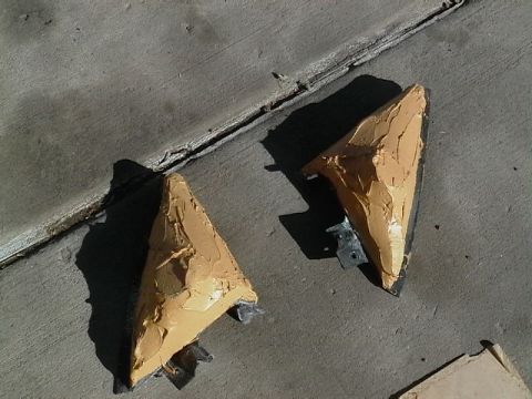1999 Ford Taurus - Two automotive parts, likely for a car, are covered in sealant and placed on a concrete surface.