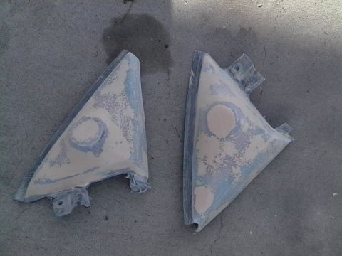 1999 Ford Taurus - Two car mirror housings, primed and filled, are shown on a concrete surface.