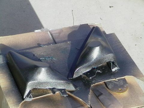 1999 Ford Taurus - Two black car mirror housings are shown on a surface, possibly undergoing repair or modification.